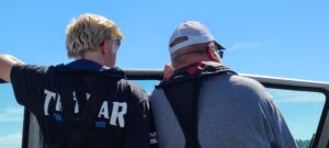 father and son navigating boat to the hot salmon spots..