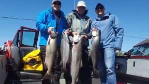 Three anglers hold large chinook salmon caught on the Oregon Coast.