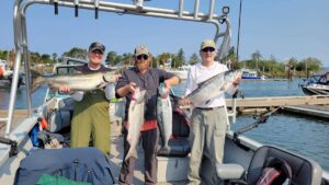 Three clients holding up three Chinook salmon and one coho salmon caught in Tillamook Bay