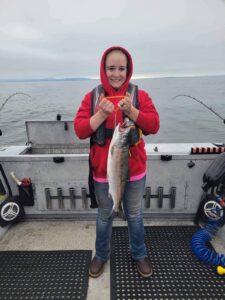 A girl on a boat holds a coho salmon she caught fishing in the Pacific Ocean off Astoria with Marvin's Guide Service.