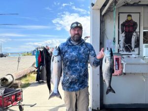 Man holding up three coho salmon back at the docks in Hammond after catching them in the ocean west of Astoria.