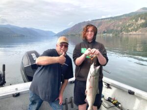 A young man holds a large Chinook salmon caught in the Columbia River near Hood River, with guide Marvin Henkel giving a thumbs-up sign.