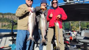 Three smiling anglers on the Marvin's Guide Service boat hold up chinook salmon they caught fishing in the Columbia River Gorge.