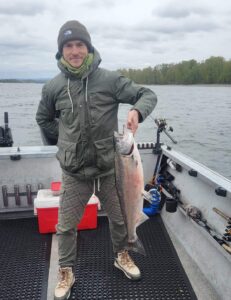 Happy fisherman holding a fresh spring chinook he caught in April 2024 on the Columbia River near Portland.